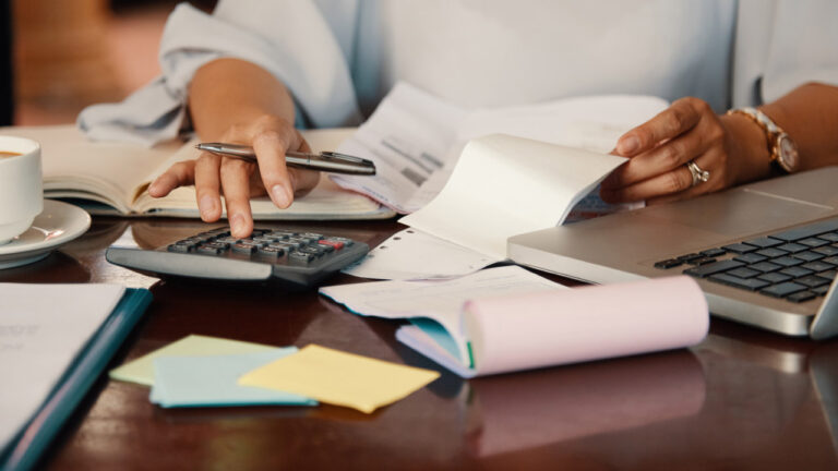 Business owner calculating payment processing fees Ireland with calculator and notepad on desk