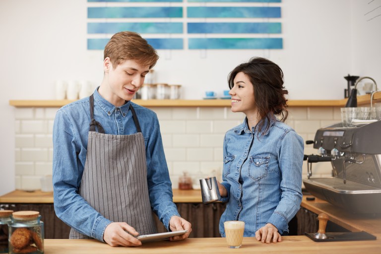 Male cashier checking same day funding data on tablet in Irish retail shop