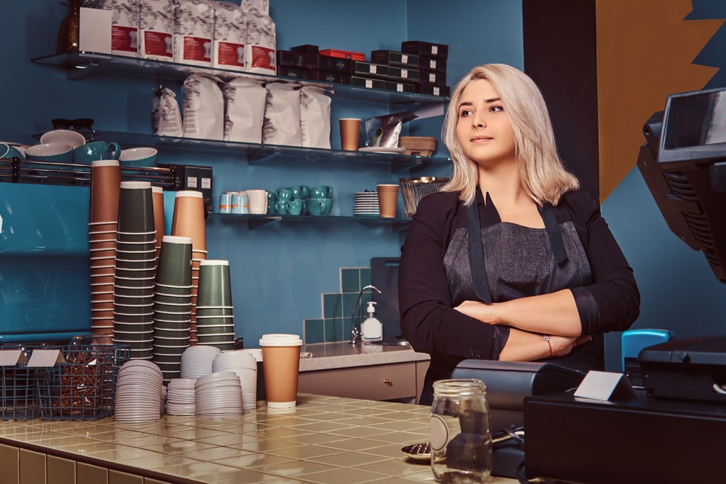 Small business owner using a card machine at a coffee shop counter