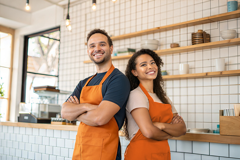 Happy small business owners in a café using payment data insights Ireland to grow their hospitality business